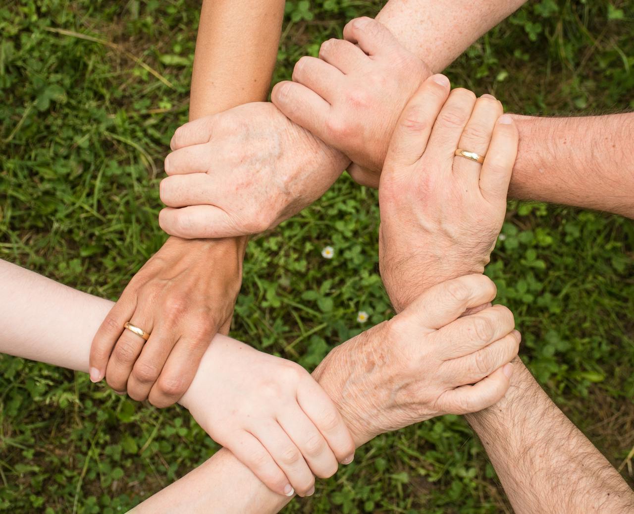People holding hands together showing unity and support in community service